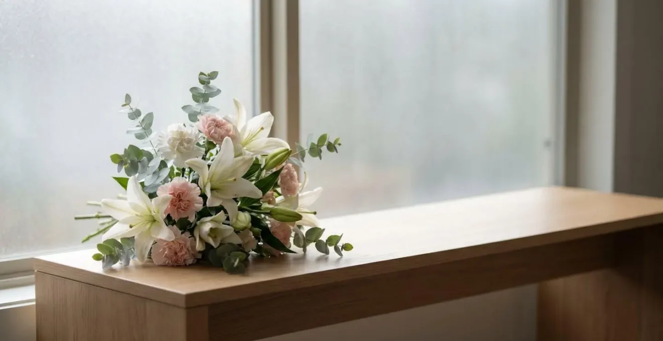 Bouquet de fleurs blanches et pastel posé avec délicatesse dans un intérieur sobre et lumineux, symbole d'un hommage funéraire respectueux