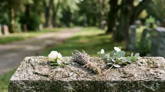 Trois bouquets de fleurs différents posés sur une même pierre tombale en granit, symbolisant trois hommages distincts au sein d'une sépulture partagée
